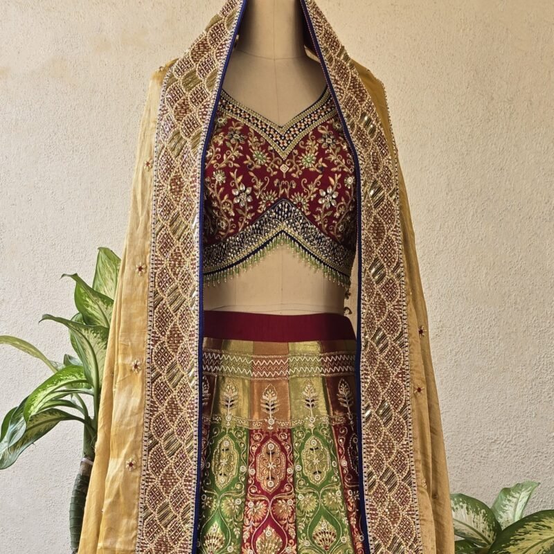Gold and red bridal lehenga with embroidered dupatta on a mannequin